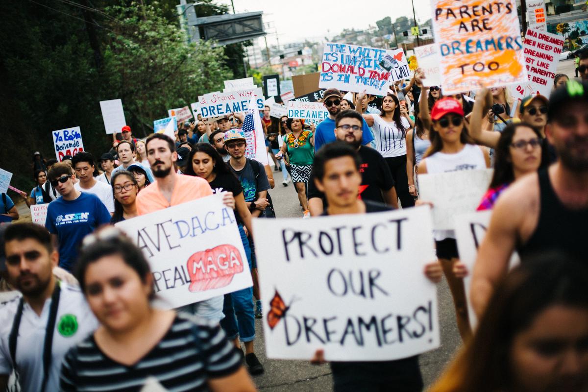 A montage of images representing current immigration issues including DACA recipients, border security, and sanctuary cities, with the Constitution in the background